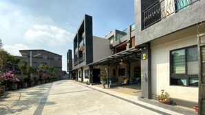A modern building with a covered entrance, potted plants, and a clear sky. - Happy Holiday Homestay (Shuishang)
