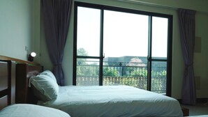 A hotel room with two beds, a nightstand, and a large window with curtains. - Happy Holiday Homestay (Shuishang)