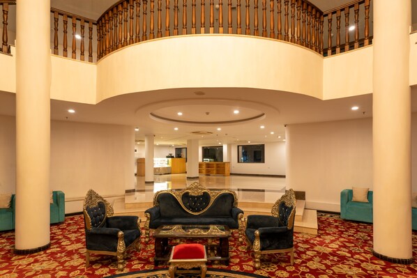 Un vestíbulo amplio con una imponente escalera, muebles elegantes y un suelo pulido.