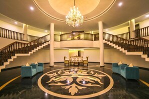 A grand lobby with a central seating area, a chandelier, and a double staircase. - Spectrum Resort & Spa, Udaipur (Udaipur)