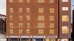 En modern byggnad med en skylt som visar texten ”The Lords ECO Inn”. Den har en fasad med ett mönster, flera fönster och ett platt tak.