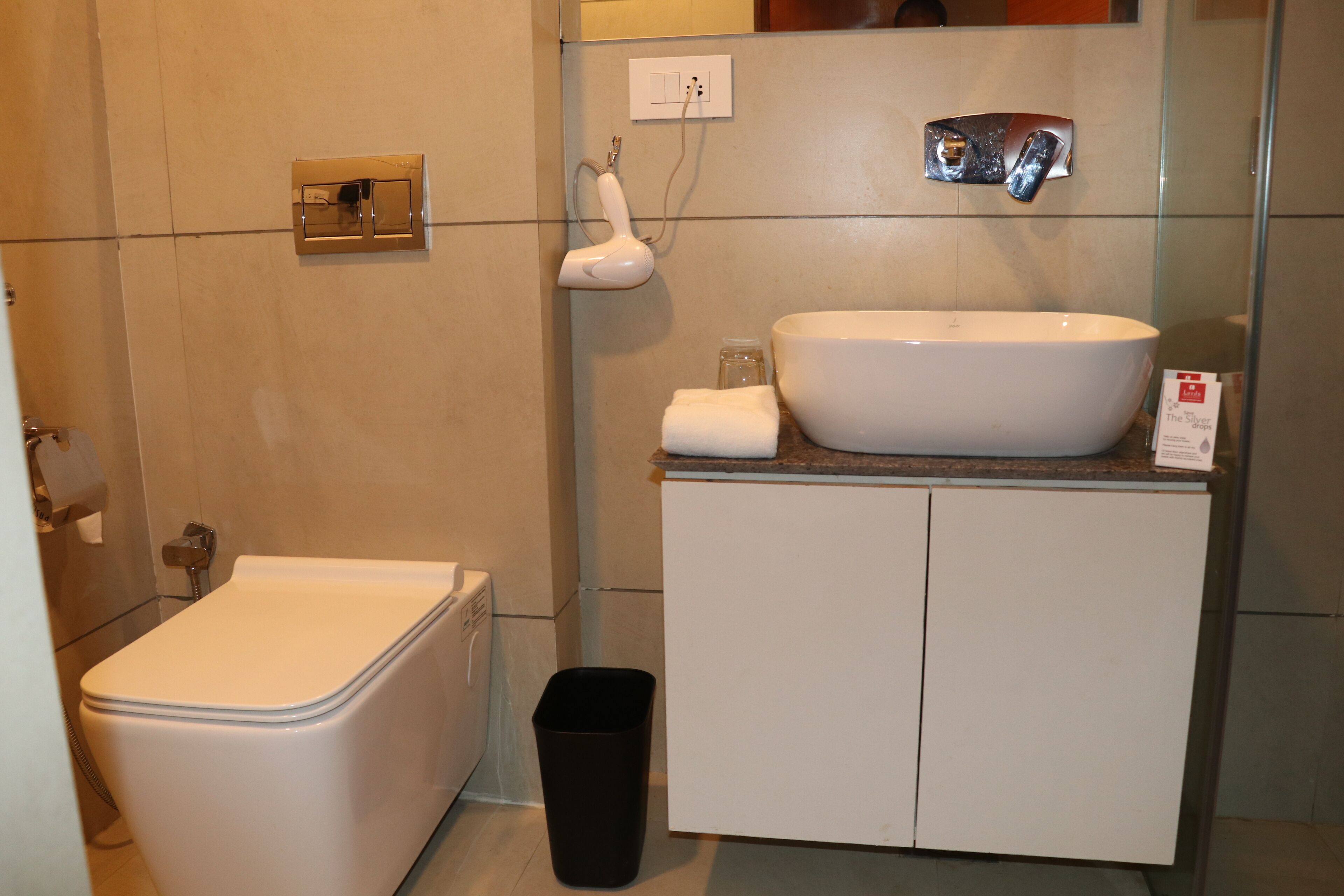 Een badkamer met een wit toilet, een witte wastafel en een zwarte prullenbak.