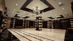 Eine großzügige Lobby mit hoher Decke, Kristalllüstern, Marmorböden und einem Billardtisch.