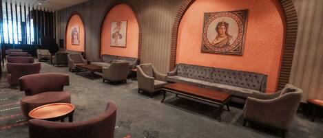 A hotel lobby with a seating area featuring sofas and armchairs, a coffee table, and a carpet with a pattern.