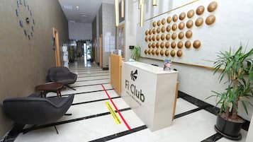 A reception area with a reception desk, seating, a wall-mounted clock, and a plant.