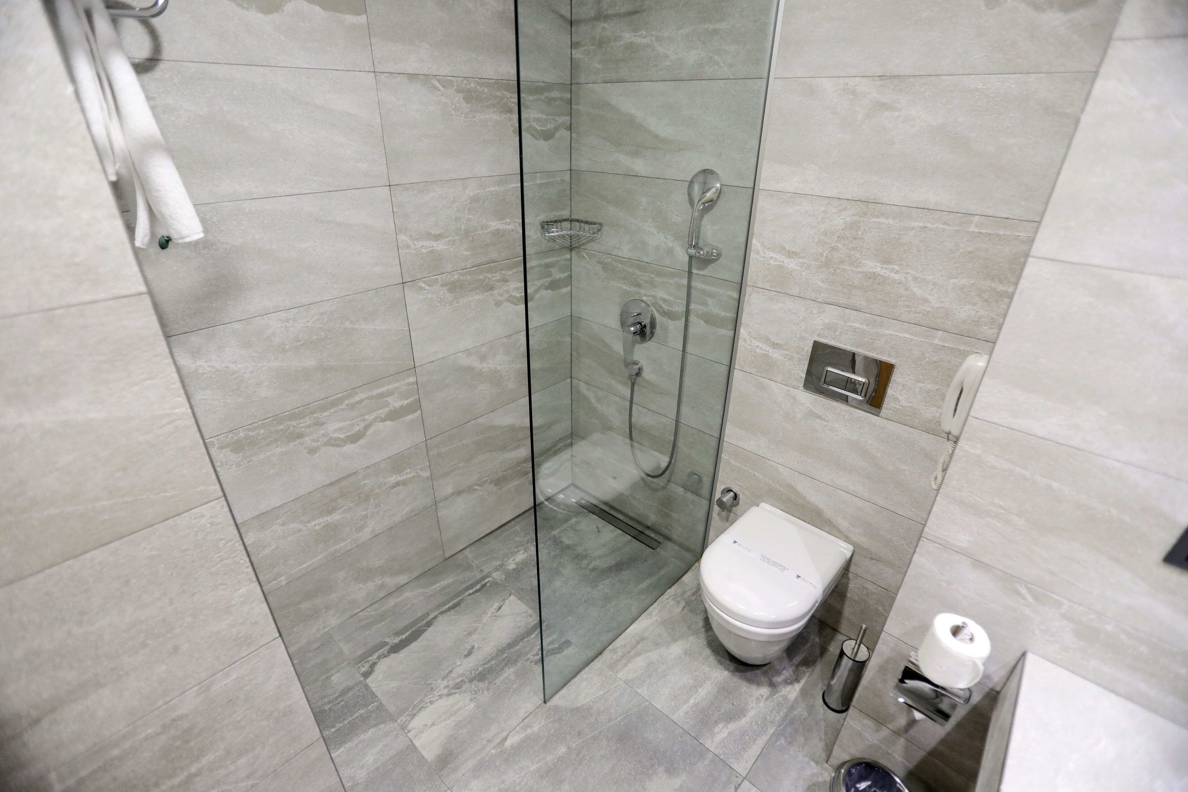 Un baño moderno con ducha de vidrio, inodoro y secador de manos.