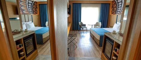 Habitación de hotel con dos camas, un pequeño comedor y vistas al exterior.