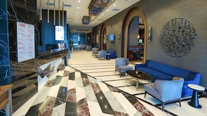 Eine geräumige Lobby mit einer Rezeption, einer Sitzecke und einem großen Wandbild.