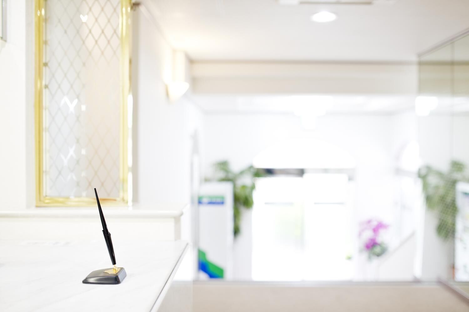 Un hall d’hôtel moderne, doté d’un comptoir d’accueil, d’une grande fenêtre ornée d’une grille décorative et d’un intérieur lumineux.