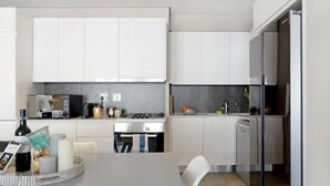 A modern kitchen with white cabinets, a gas stove, and a dishwasher. - Lily By Stay Amazing (Cape Town)