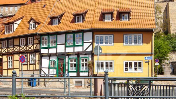 Un bâtiment européen traditionnel, doté d’un toit en tuiles, d’une tour imposante et d’un pont piétonnier.