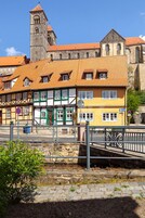 Ein traditionelles europäisches Gebäude mit einem Ziegeldach, einem markanten Turm und einer Fußgängerbrücke.