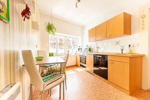Eine moderne Küche mit Holzausstattung, einem Esstisch mit Stühlen und einem großen Fenster, das für natürliches Licht sorgt.