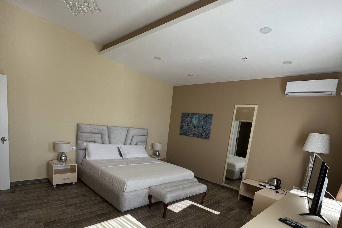 A modern hotel room with a large bed, bedside tables, a desk, and a chair.