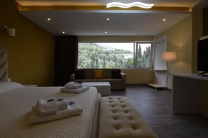 A hotel room with a large bed, a sofa, a desk, and a view of the outdoors. - Monte Mare Hotel (Vlorë)