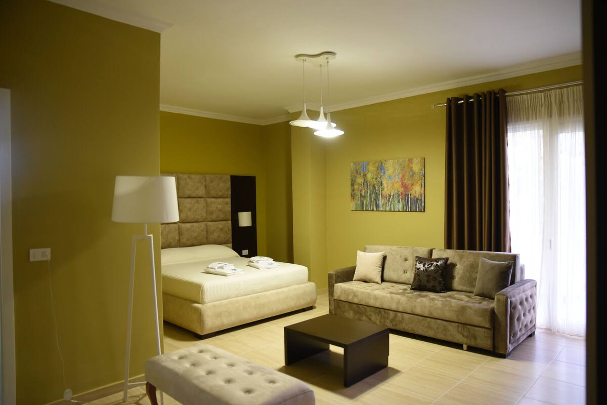 A modern living room with a bed, a sofa, a coffee table, and a floor lamp.