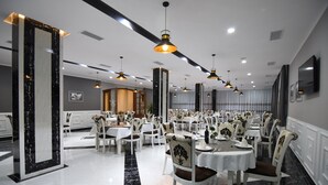 A spacious dining area with multiple round tables and chairs, elegant chandeliers, and a polished marble floor. - Monte Mare Hotel (Vlorë)