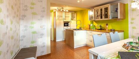 A compact kitchen with a dining area, featuring a refrigerator, microwave, and cabinets.