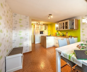 A compact kitchen with a dining area, featuring a refrigerator, microwave, and cabinets.