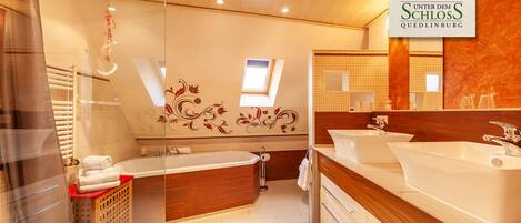 Ein modernes Badezimmer mit einer großzügigen Badewanne, zwei Waschbecken und einer separaten Duschkabine.