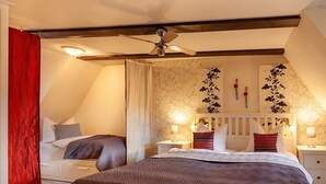 A bedroom with a large bed, a ceiling fan, and a nightstand with a lamp. - Apartment unter dem Schloss (Quedlinburg)
