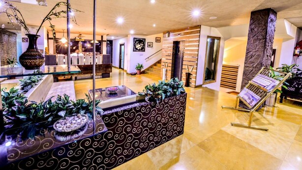 A spacious lobby with a central seating area, a staircase, and a reception desk. - Raghu Mahal Hotel (Udaipur)