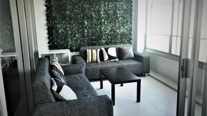 A modern living room with grey sofas and a black coffee table, a green vertical garden wall, and a sliding glass door leading to a balcony. - Private Apartments at Q1 (Surfers Paradise)