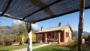 A house with a tiled roof, a covered patio, and a stone pathway leading to the entrance. - Villa Miramare (Camaiore)