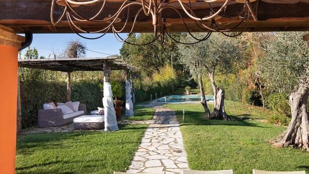A covered outdoor seating area with a stone pathway leading to a pool. - Villa Miramare (Camaiore)