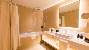 A modern bathroom with a bathtub, a large mirror, and a vanity with a sink and towel rack.