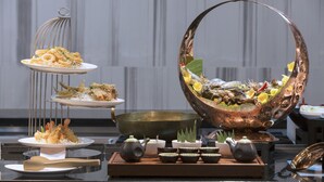 A buffet setup with seafood dishes, a large copper bowl, and traditional tea sets. - Zealax Hotel & Residence (Yangon)
