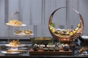 Montaje de bufé con mariscos, un recipiente de cobre grande y juegos de té tradicionales.