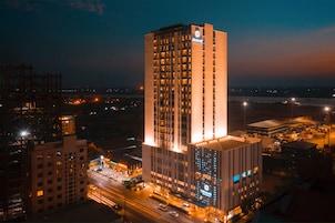Un hotel de gran altura con varios pisos, ventanas iluminadas y un letrero llamativo.