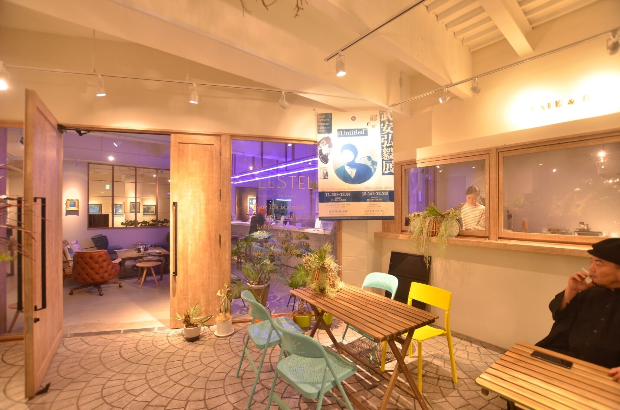 An indoor seating area with tables and chairs, a wooden floor, and potted plants.