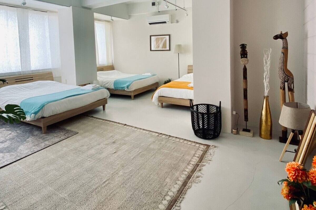 A spacious bedroom with two beds, a large window, and a modern ceiling design.