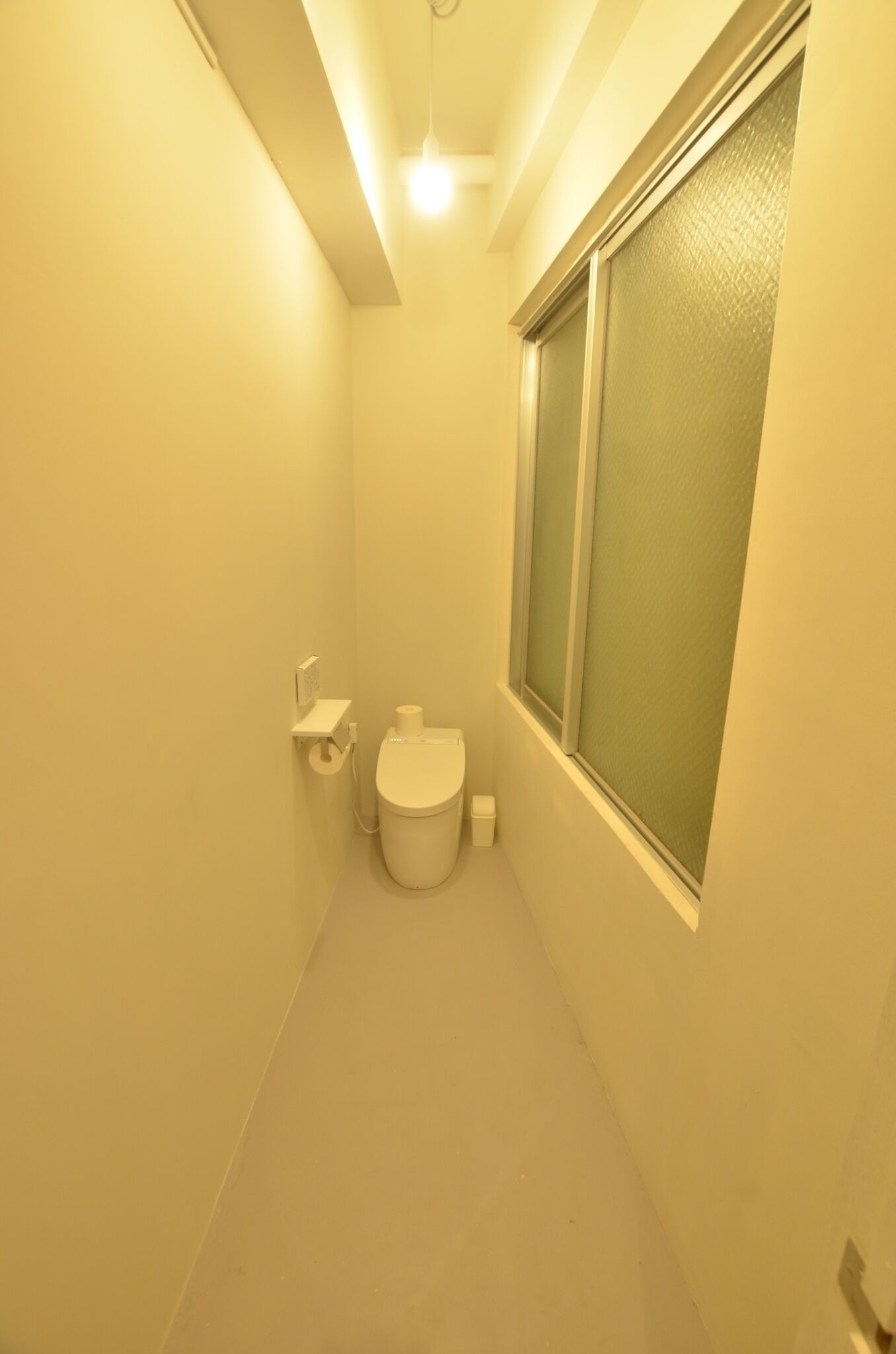 Une petite salle de bain comprenant des toilettes, un petit lavabo et une fenêtre.