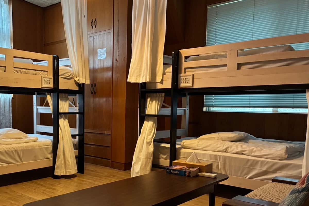 A dormitory room with bunk beds, wooden walls, and curtains.