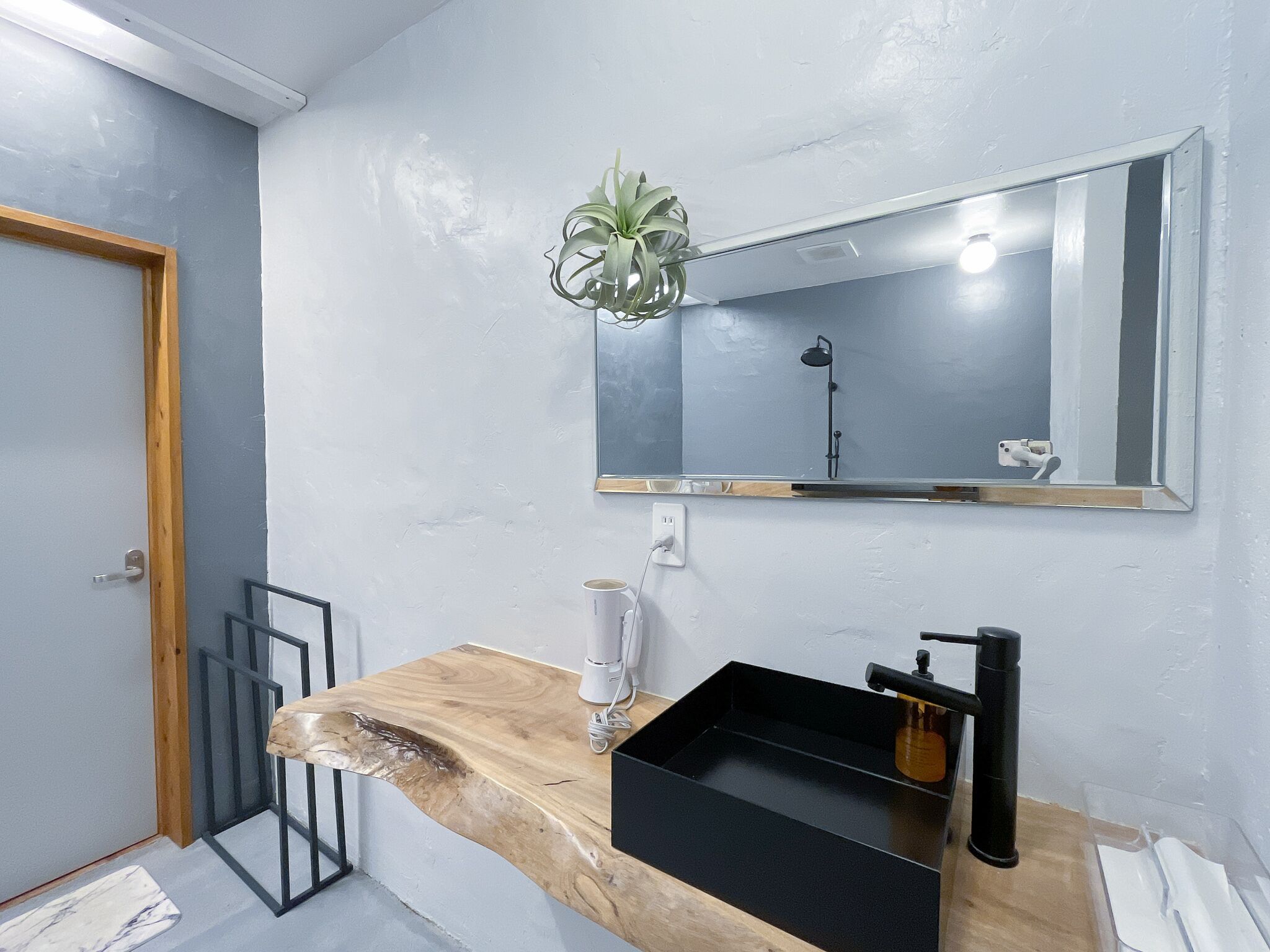 Un baño moderno con tocador de madera, lavabo negro y espejo.
