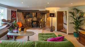 A cozy living room with a stone fireplace, green sofas, and a large window. - Samsara Retreat and Yoga - Adults Only (Maidstone)