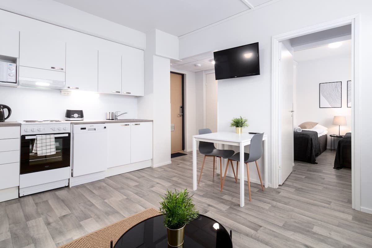A modern kitchen with white cabinets, a built-in oven, and a dining area with a table and chairs.