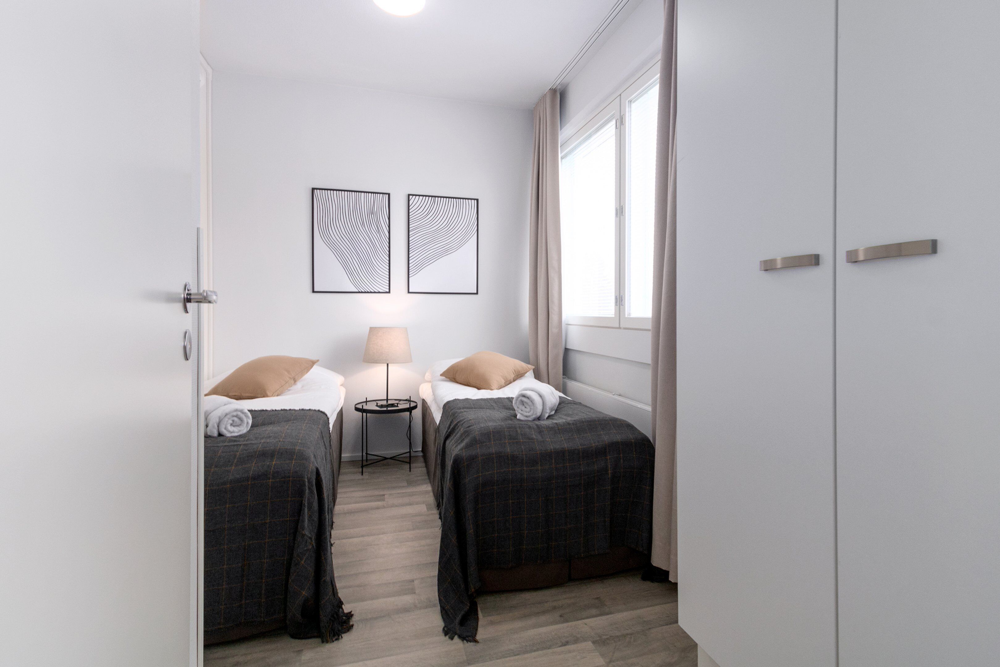 Una habitación de hotel con dos camas, una mesita con una lámpara y una obra de arte en la pared.