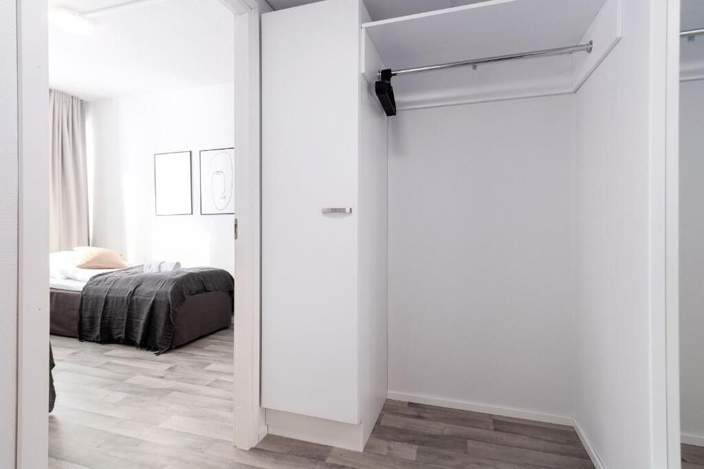 A bedroom with a bed, a wardrobe, and a bathroom with a towel rack.