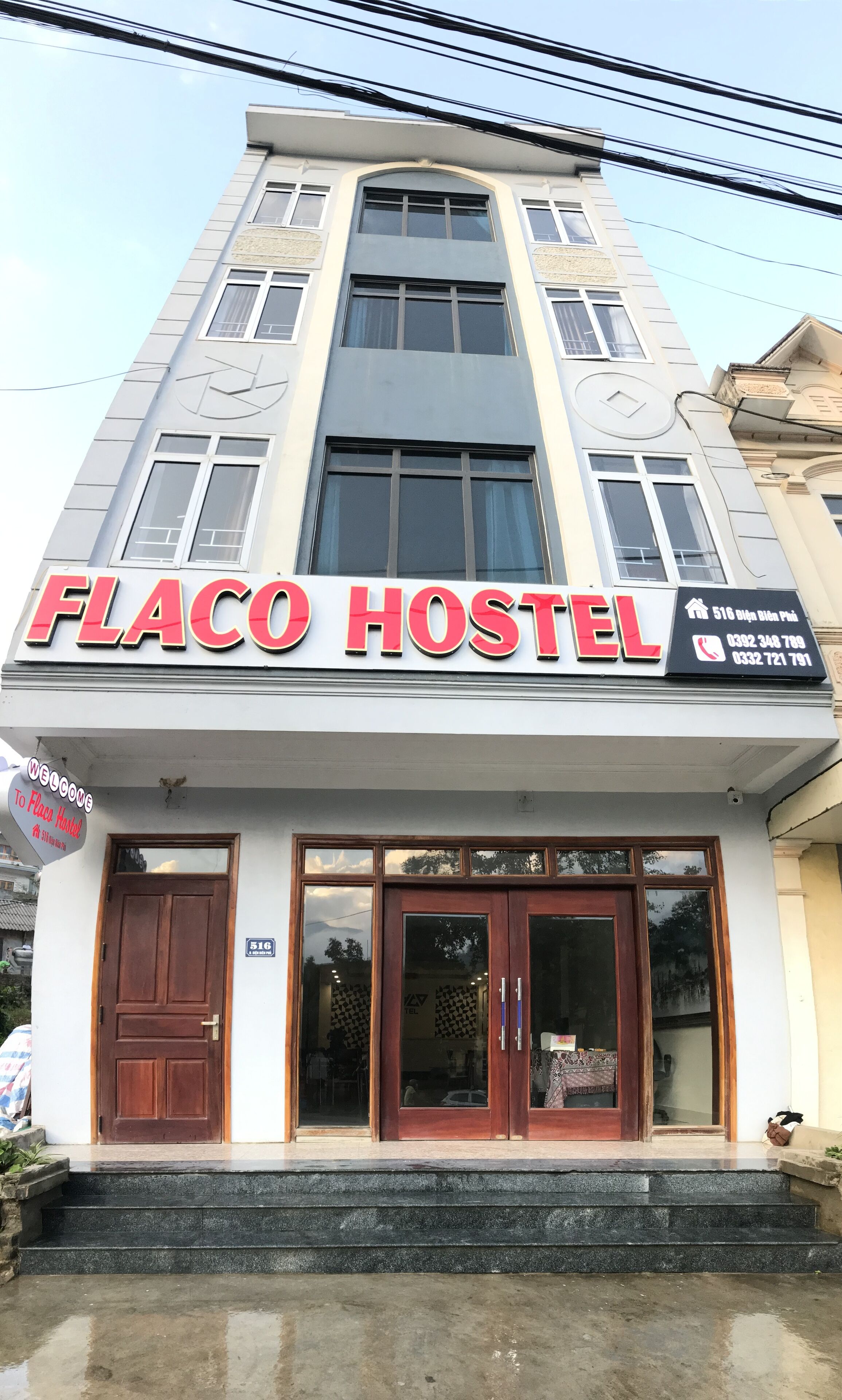 En bygning med et skilt, der viser "FLACO HOSTEL", og et velkomstskilt.