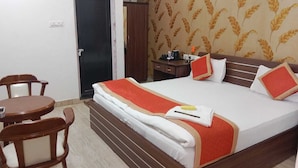 A hotel room with a bed, a desk, and two chairs. - Hotel Shalimar Palace (Raebareli)