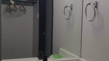 A bathroom with a large mirror, a sink, and a towel rack.