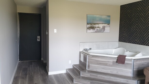Ein modernes Badezimmer mit freistehender Badewanne, Holzboden und Wandverkleidung in Zickzackmuster.