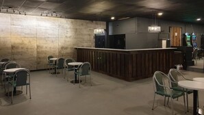 Ein modernes Restaurant mit Barbereich, runden Tischen und Stühlen.