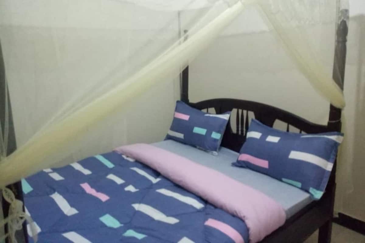 Una cama con dosel, un edredón estampado y almohadas.