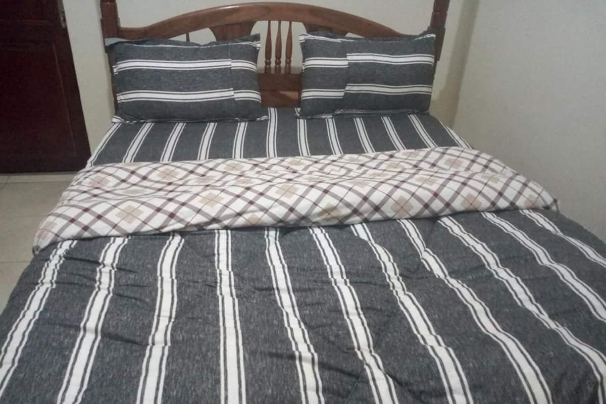 Una cama con ropa de cama a rayas y una manta escocesa.