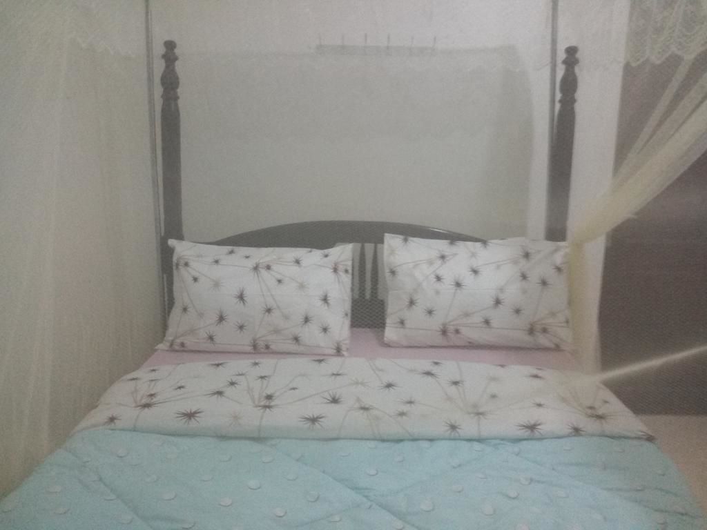A bed with a canopy, two pillows with a star pattern, and a blue quilt.